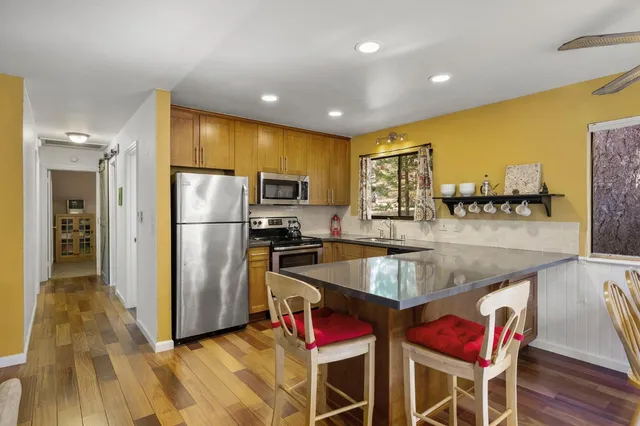 a kitchen with stainless steel appliances granite countertop a refrigerator a stove and a wooden floors
