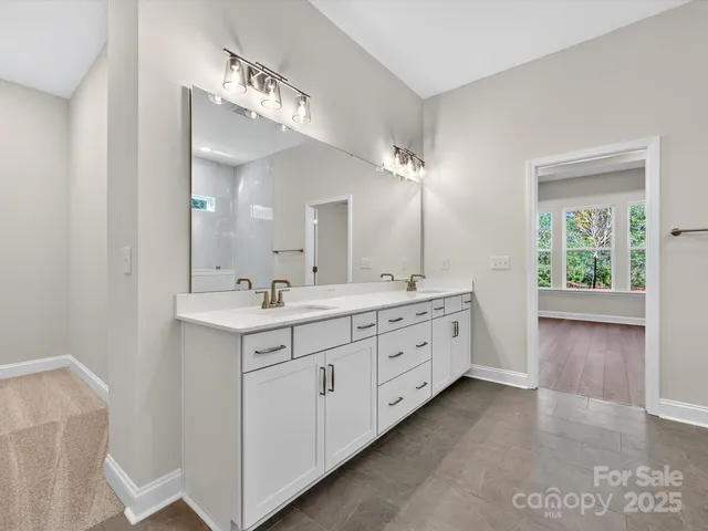 a spacious bathroom with double vanity a mirror and a sink