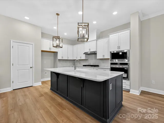 a kitchen with kitchen island stainless steel appliances a sink cabinets and wooden floor