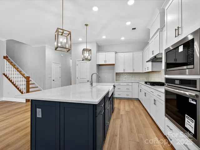 a large kitchen with stainless steel appliances kitchen island granite countertop a sink a stove and cabinets