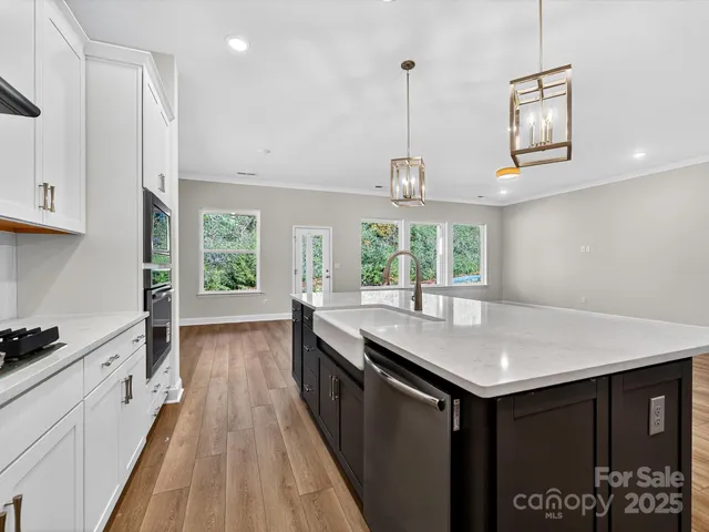 a kitchen with stainless steel appliances granite countertop a stove a sink and a refrigerator with wooden floor