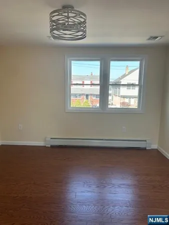 an empty room with wooden floor chandelier fan and windows