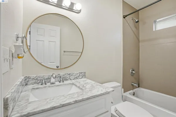 a bathroom with a granite countertop toilet a sink and a mirror