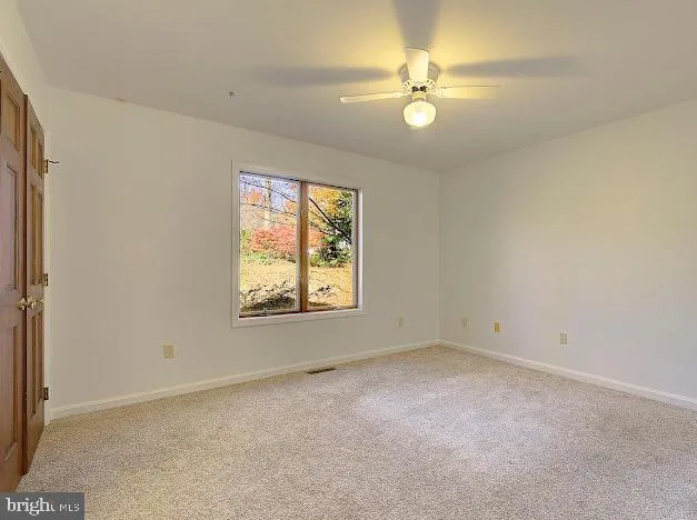 an empty room with windows and ceiling fan view