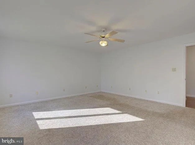 a view of an empty room with a window and a kitchen