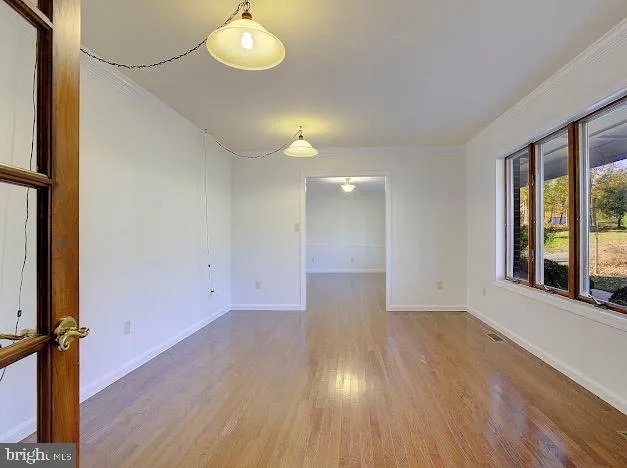 a view of an empty room with wooden floor and a window