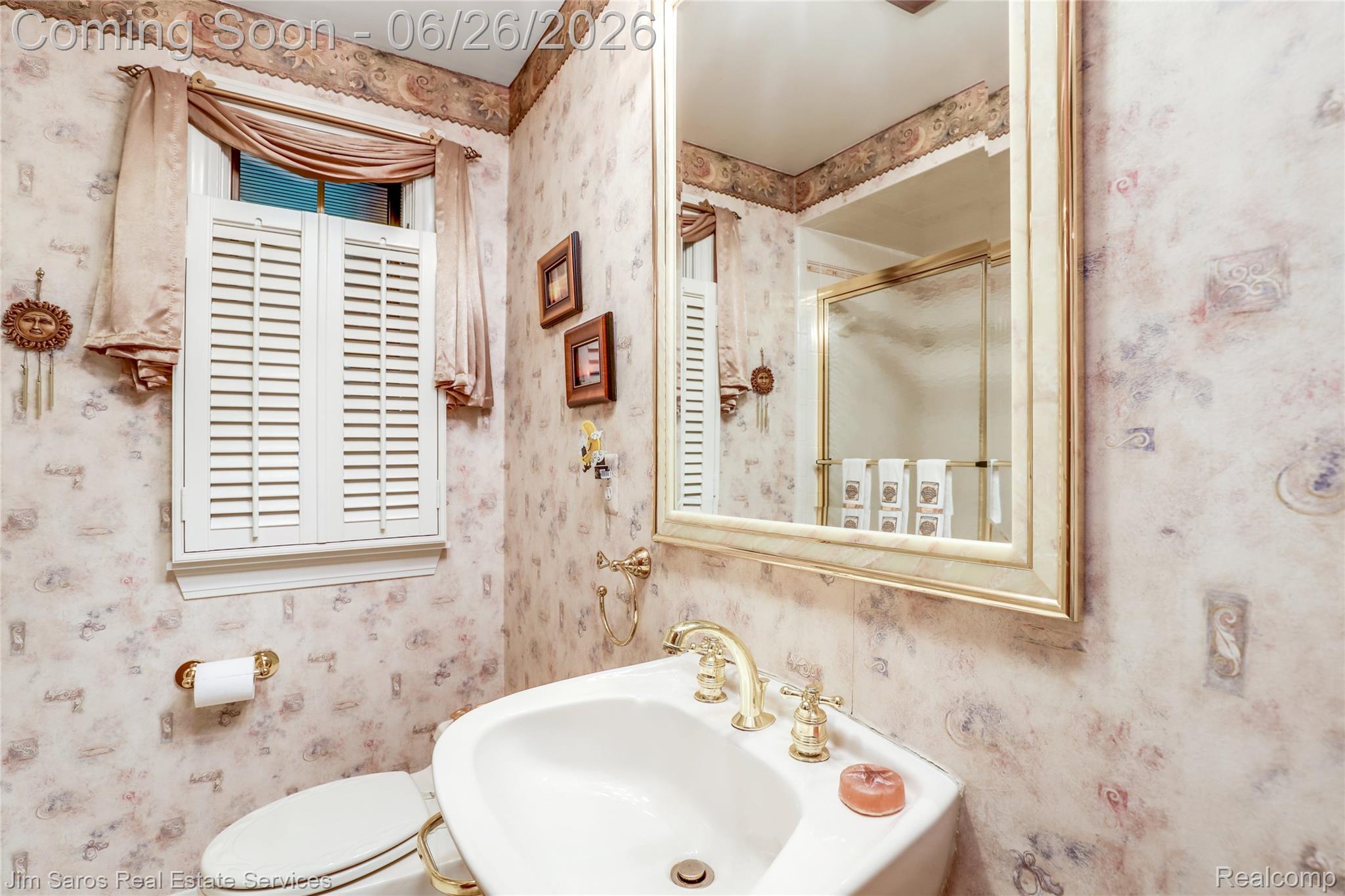 764 Harcourt Road Grosse Pointe, MI 48230 - Photo 13 of 42 Bathroom featuring a corner sink with brass fixtures, a framed mirror, and a window with white louvered shutters
