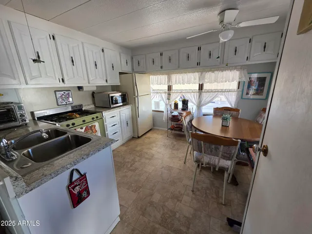 a kitchen with stainless steel appliances granite countertop a refrigerator a sink dishwasher a stove a dining table and chairs with wooden floor