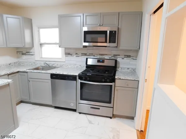 a kitchen with granite countertop white cabinets and stainless steel appliances