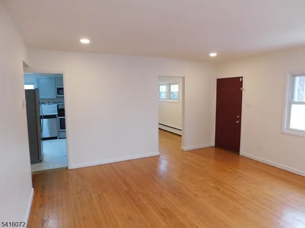 a view of an empty room with wooden floor and closet