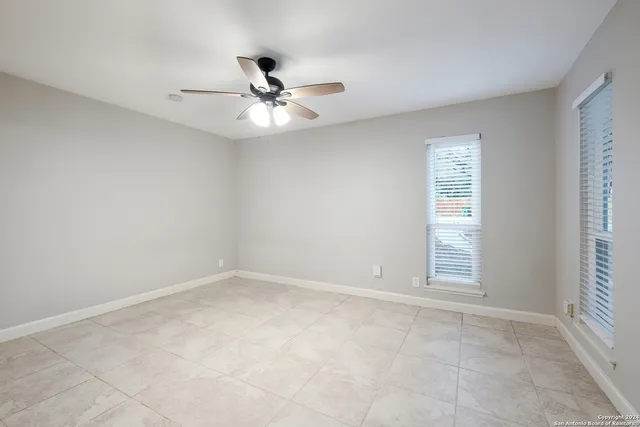 an empty room with windows and fan