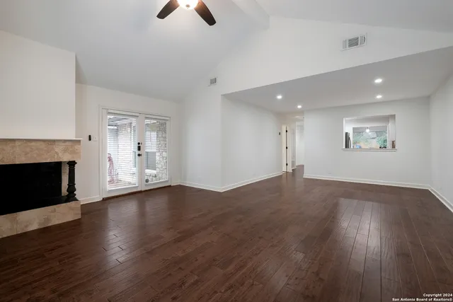 an empty room with wooden floor fireplace and windows
