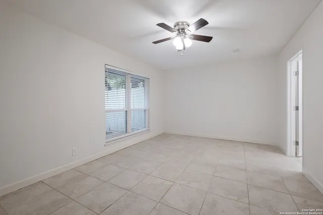 an empty room with windows and chandelier fan
