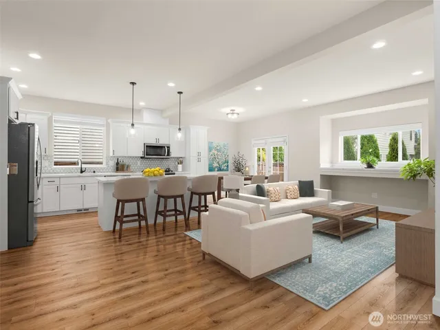 a living room with stainless steel appliances kitchen island granite countertop a table chairs and a refrigerator