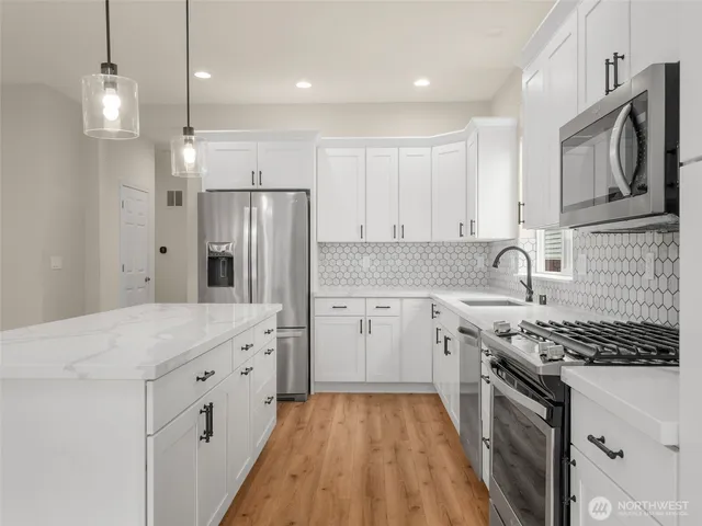 a kitchen with stainless steel appliances a stove a sink a refrigerator and cabinets