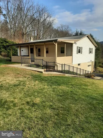 a front view of house with yard and trees in the background