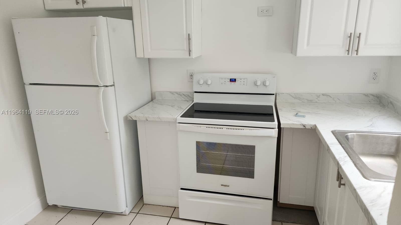4108 Riverside Drive, Unit 2 Coral Springs, FL 33065 - Photo 2 of 11 a kitchen with white cabinets and a refrigerator