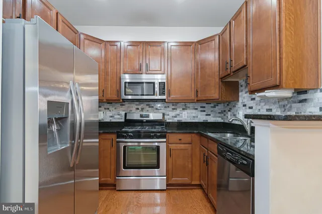a kitchen with stainless steel appliances granite countertop a stove a microwave and a refrigerator