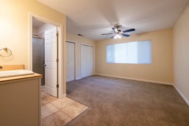 an empty room with windows and fan