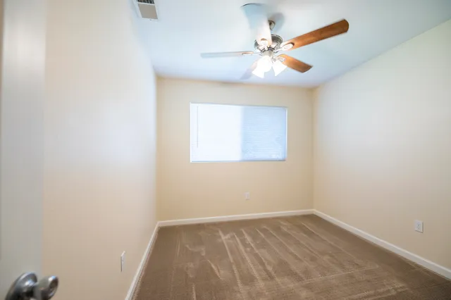 an empty room with a window and a fan