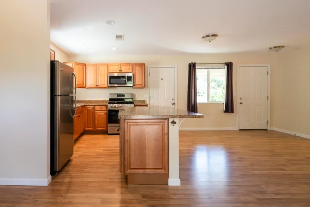a kitchen with stainless steel appliances granite countertop a stove top oven a sink and a refrigerator