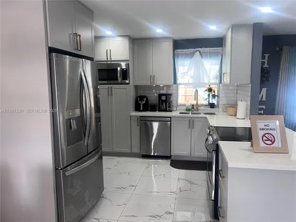 a kitchen with stainless steel appliances granite countertop a refrigerator a stove a sink and a microwave