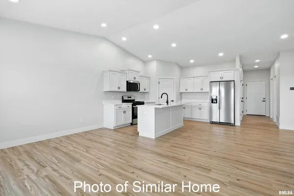 a view of kitchen with granite countertop refrigerator and white cabinets