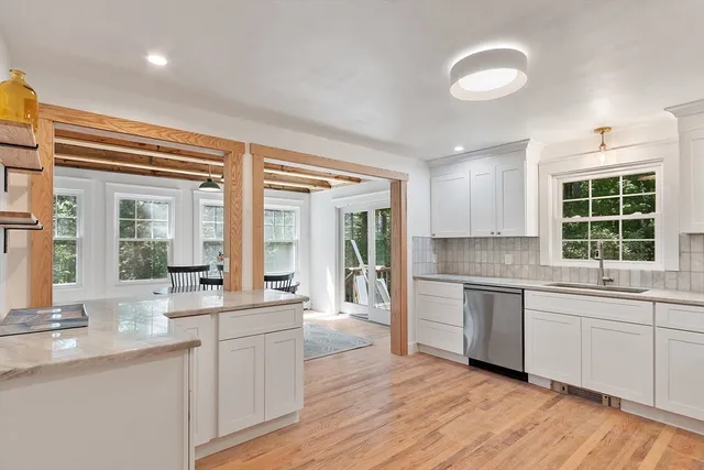 a large kitchen with kitchen island a large window cabinets a sink and stainless steel appliances