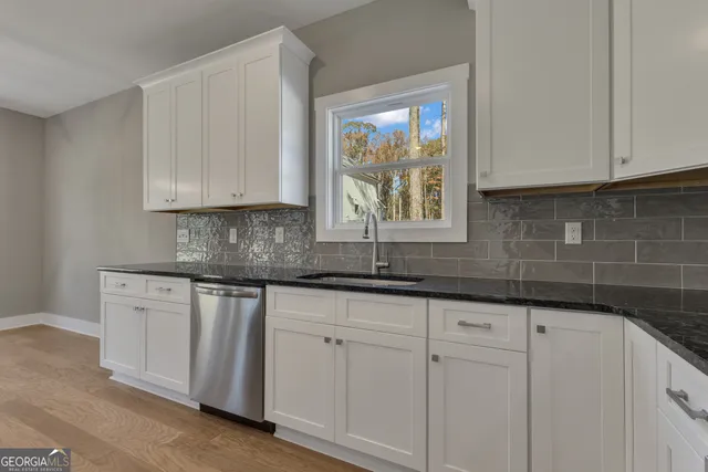 a kitchen with granite countertop white cabinets sink and stainless steel appliances
