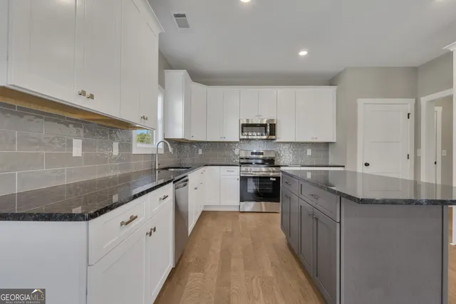 a view of an empty room with a window and kitchen view