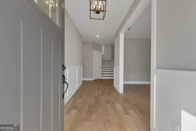 a view of an empty room with a window and chandelier