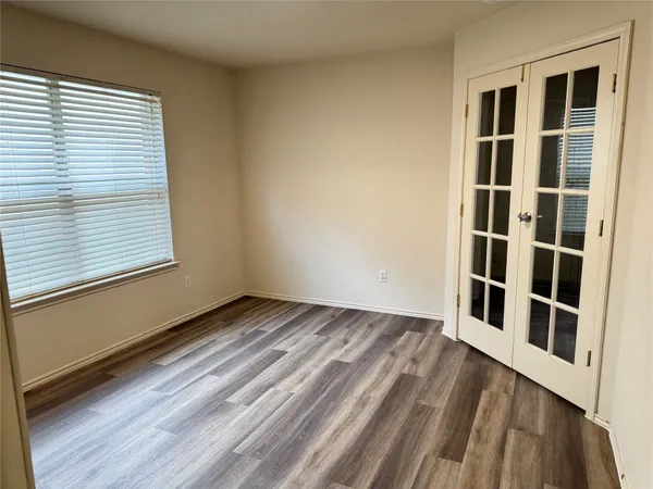 a view of an empty room with wooden floor and a window