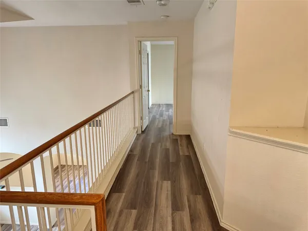 a view of a hallway with wooden floor and staircase