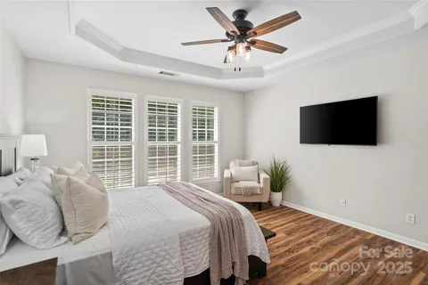 a bedroom with a bed a tv and wooden floor