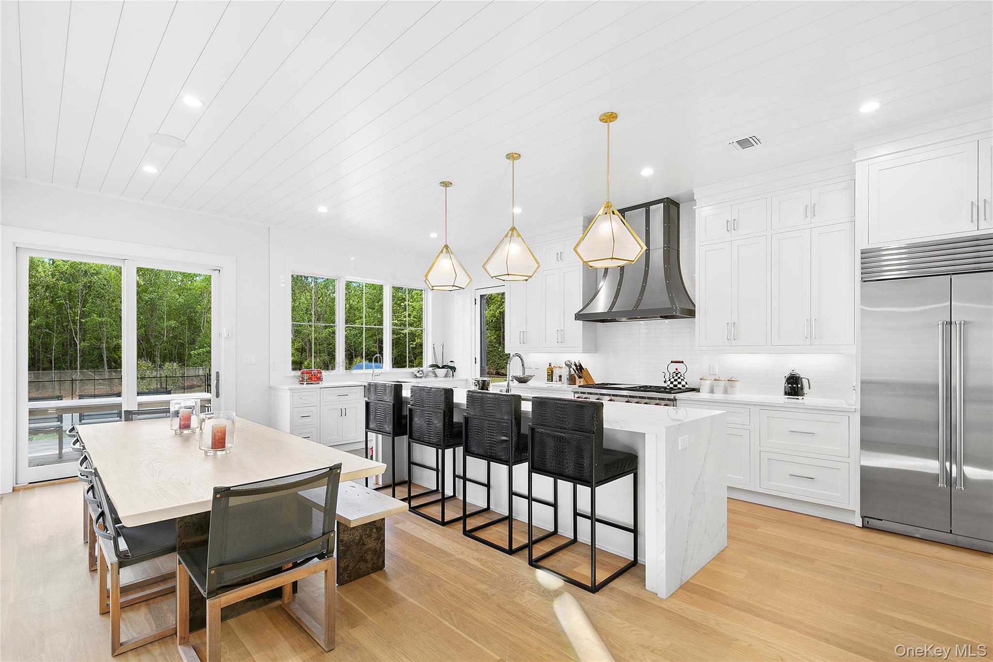 94 Merchants Path Sagaponack, NY 11962 - Photo 6 of 15 a kitchen with stainless steel appliances granite countertop a stove a refrigerator a kitchen island a dining table and chairs with wooden floor
