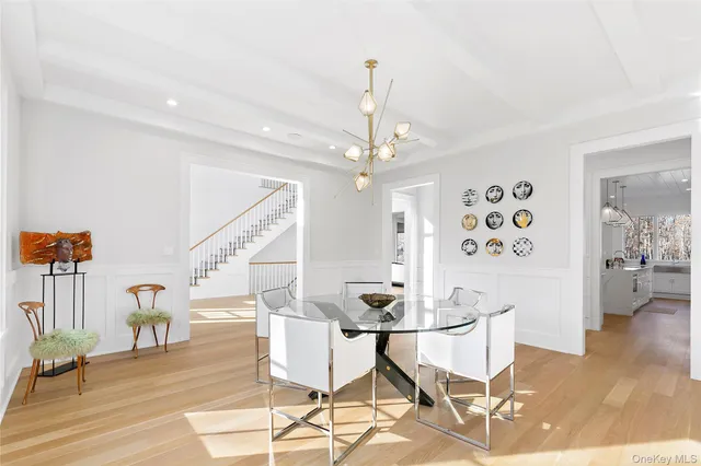 a dining room with wooden floor a chandelier a wooden table and chairs