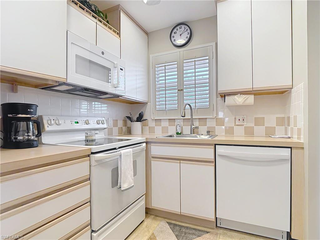 150 Turtle Lake Court, Unit 309 Naples, FL 34105 - Photo 13 of 42 Kitchen featuring white appliances, a sink, and decorative backsplash