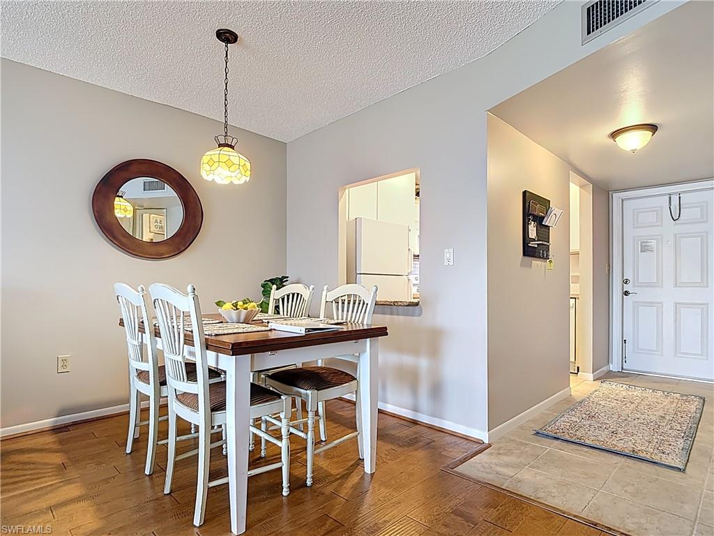 150 Turtle Lake Court, Unit 309 Naples, FL 34105 - Photo 14 of 42 Dining area with a textured ceiling, wood finished floors, and baseboards