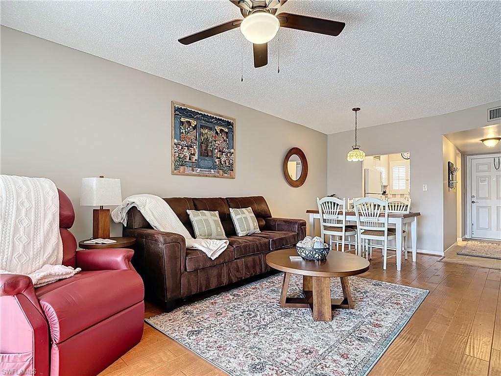 150 Turtle Lake Court, Unit 309 Naples, FL 34105 - Photo 18 of 42 Living room featuring ceiling fan, a textured ceiling, and wood finished floors