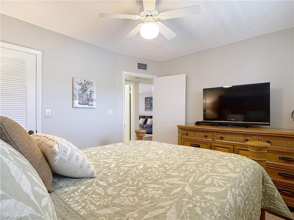 150 Turtle Lake Court, Unit 309 Naples, FL 34105 - Photo 19 of 42 Bedroom with a textured ceiling and a ceiling fan