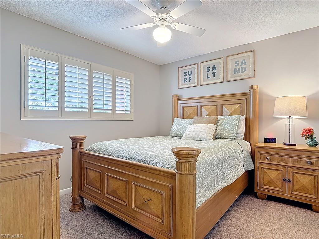 150 Turtle Lake Court, Unit 309 Naples, FL 34105 - Photo 20 of 42 Bedroom with light colored carpet, multiple windows, a ceiling fan, and a textured ceiling