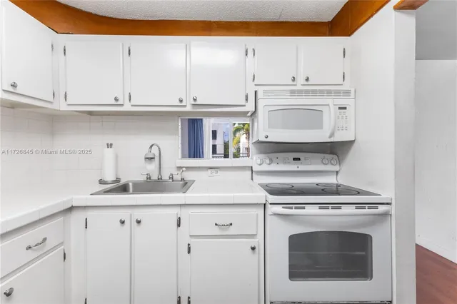 a kitchen with granite countertop white cabinets and white appliances