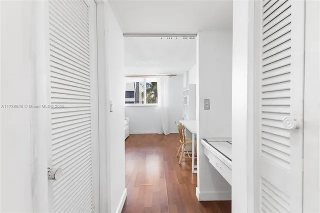 a view of a hallway with wooden floor and closet