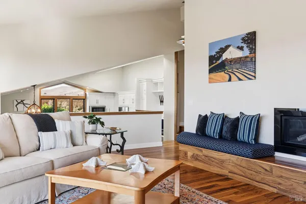 a living room with stainless steel appliances kitchen island granite countertop a stove a sink a refrigerator and white cabinets with wooden floor