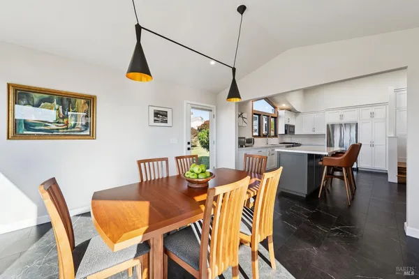 a kitchen with stainless steel appliances refrigerator stove dining table and chairs