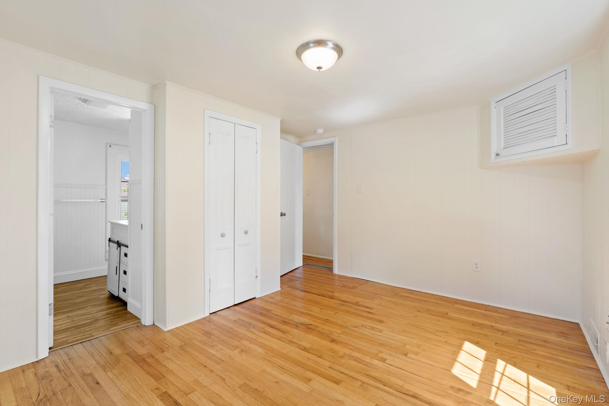 1 2nd Street Walden, NY 12586 - Photo 17 of 42 Unfurnished bedroom featuring light wood finished floors, a closet, and wooden walls