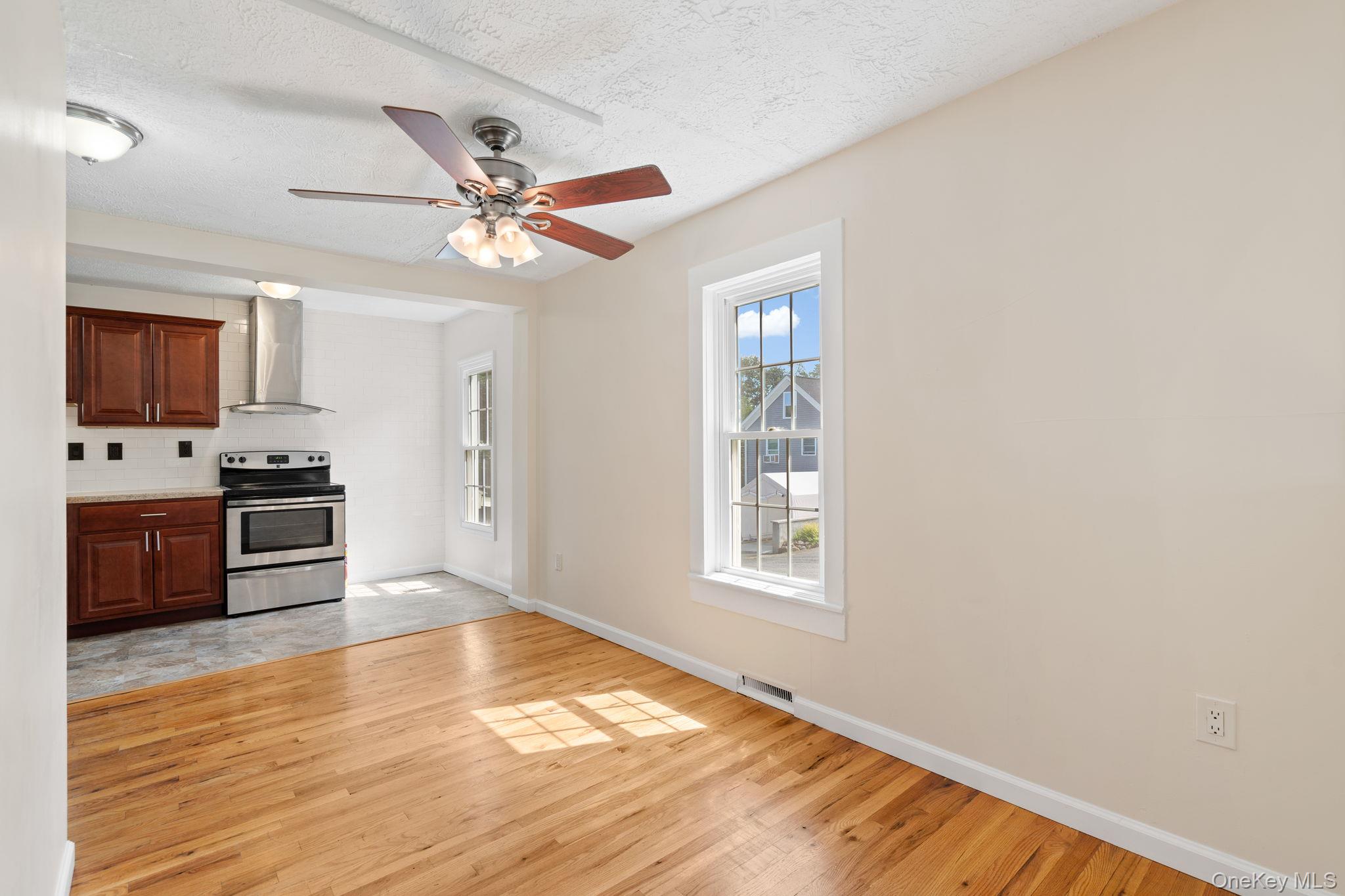 1 2nd Street Walden, NY 12586 - Photo 6 of 42 Kitchen with electric range, ceiling fan, wall chimney range hood, light countertops, and light wood finished floors