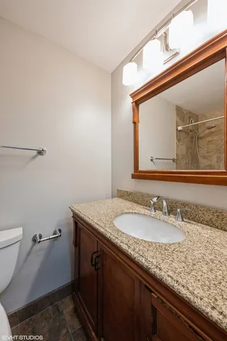 a bathroom with a granite countertop sink a toilet and a mirror
