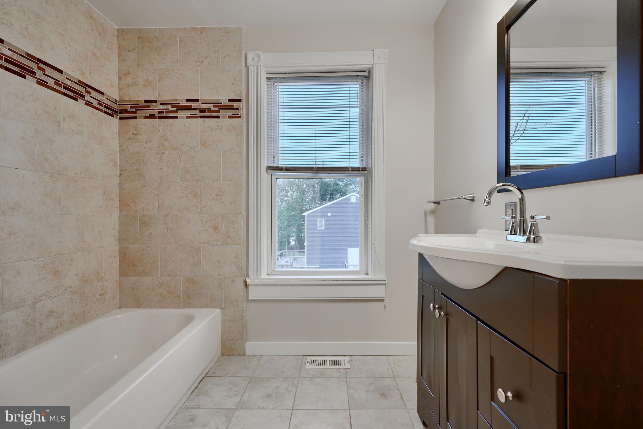 1817 Summit Avenue Baltimore, MD 21227 - Photo 17 of 28 a bathroom with a sink a bathtub and a shower