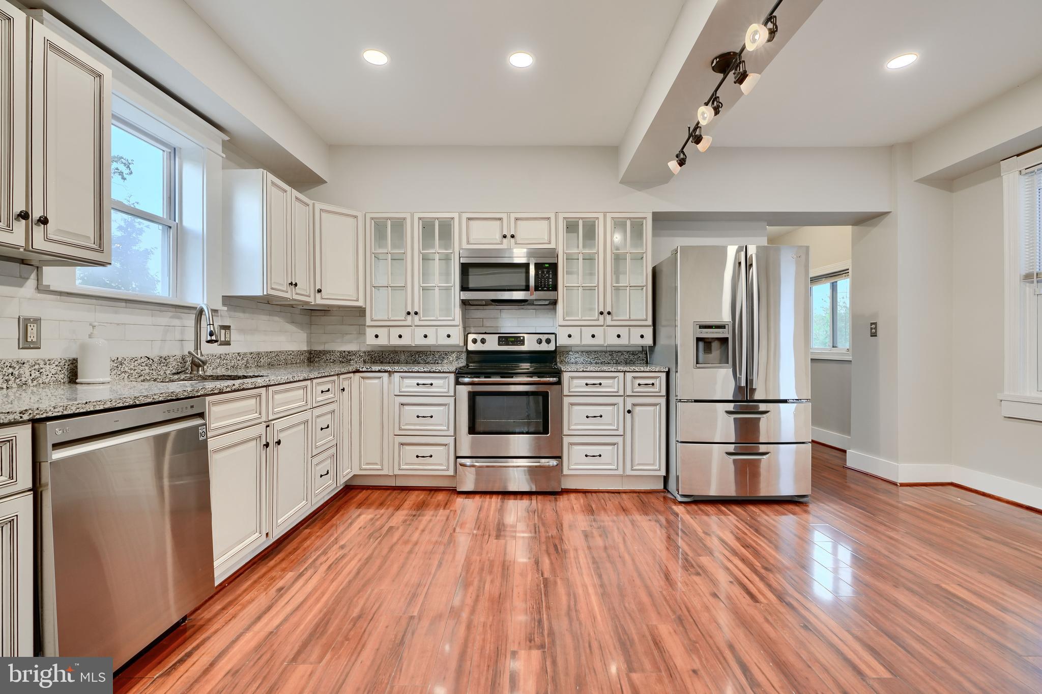 1817 Summit Avenue Baltimore, MD 21227 - Photo 3 of 28 a kitchen with wooden floors stainless steel appliances and window